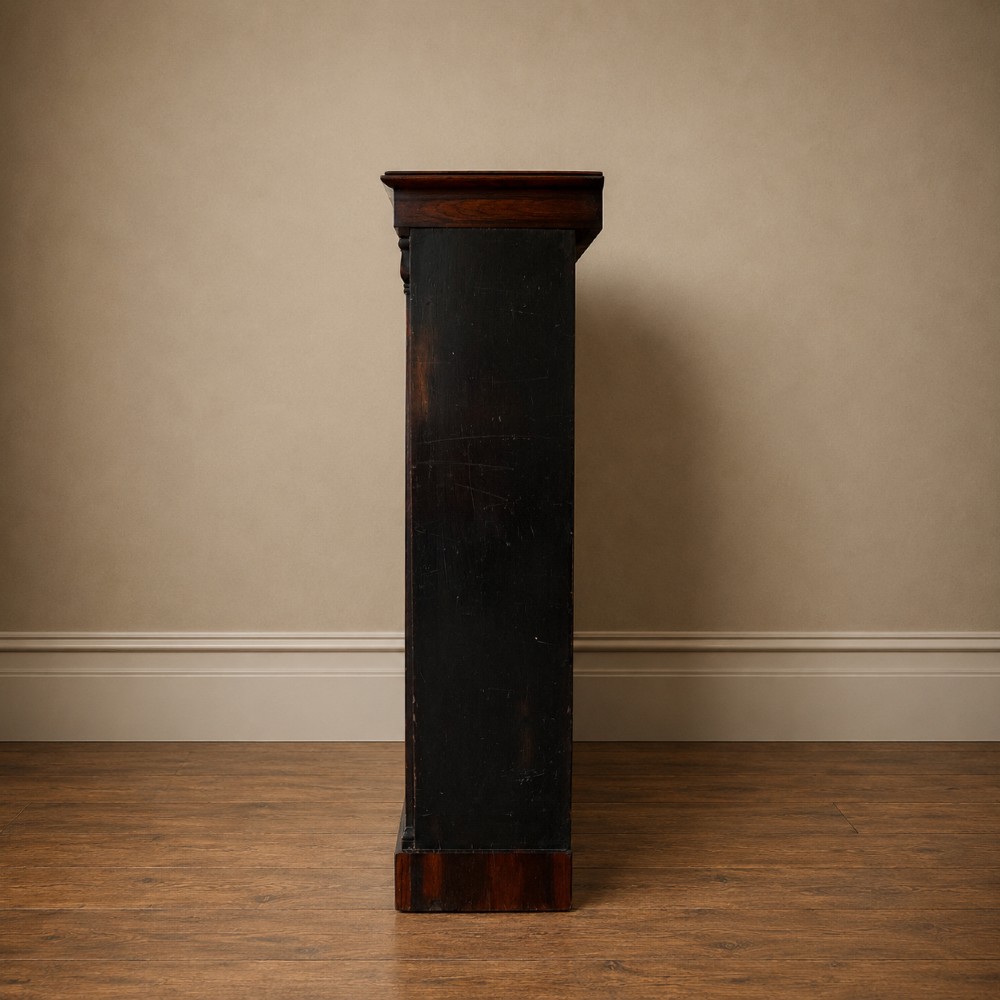 An antique William IV rosewood open bookcase featuring two adjustable shelves, a solid plinth base, and carved scroll capitals atop side pilasters. View XIII