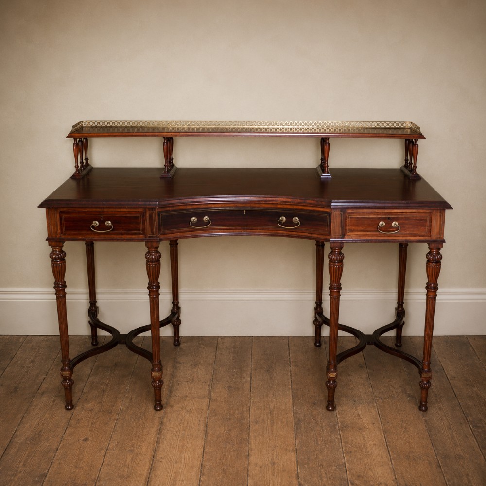 A Victorian rosewood writing desk featuring a brass gallery shelf, three drawers with brass handles, turned fluted legs, and curved stretchers. View XV