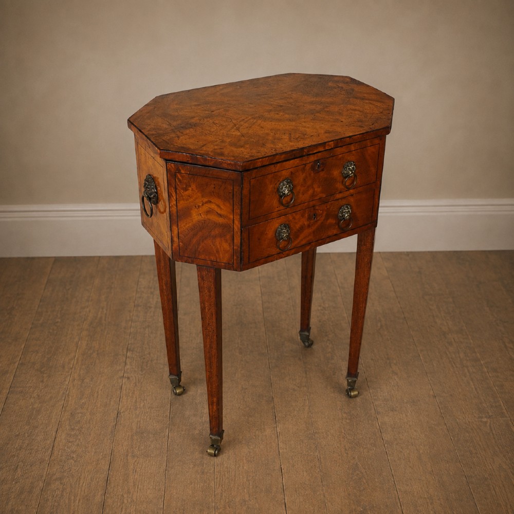 An octagonal George III satinwood work table with two drawers, lion mask ring handles, and tapered legs ending in brass castors. View VIII