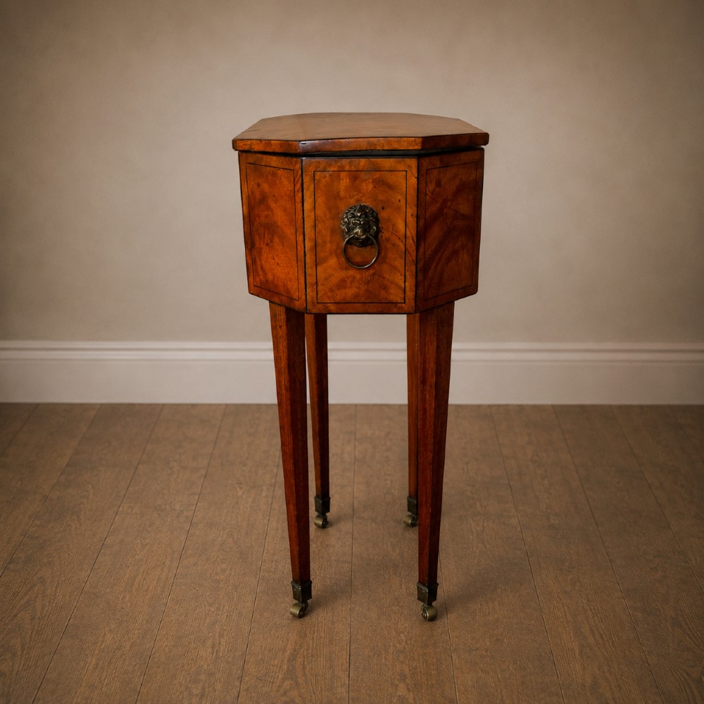 An octagonal George III satinwood work table with two drawers, lion mask ring handles, and tapered legs ending in brass castors. View IX
