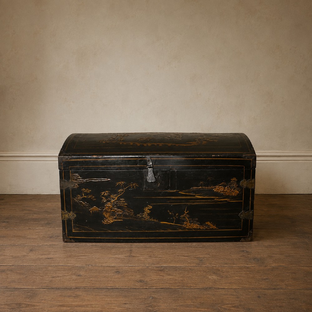 A 19th-century black lacquered domed storage trunk decorated with gilded chinoiserie landscape scenes and metal corner hardware.