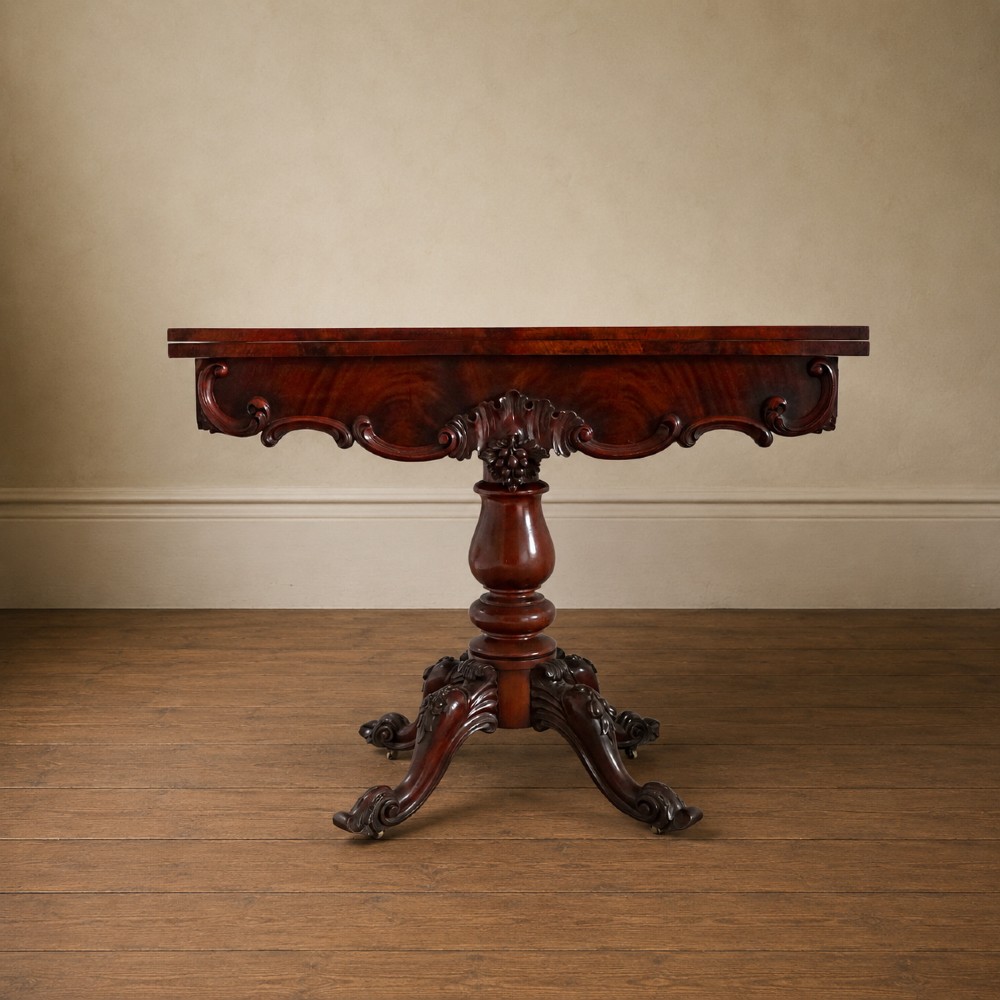 A Victorian figured mahogany card table featuring a turnover top, carved frieze, turned pedestal, and scroll legs with castors.