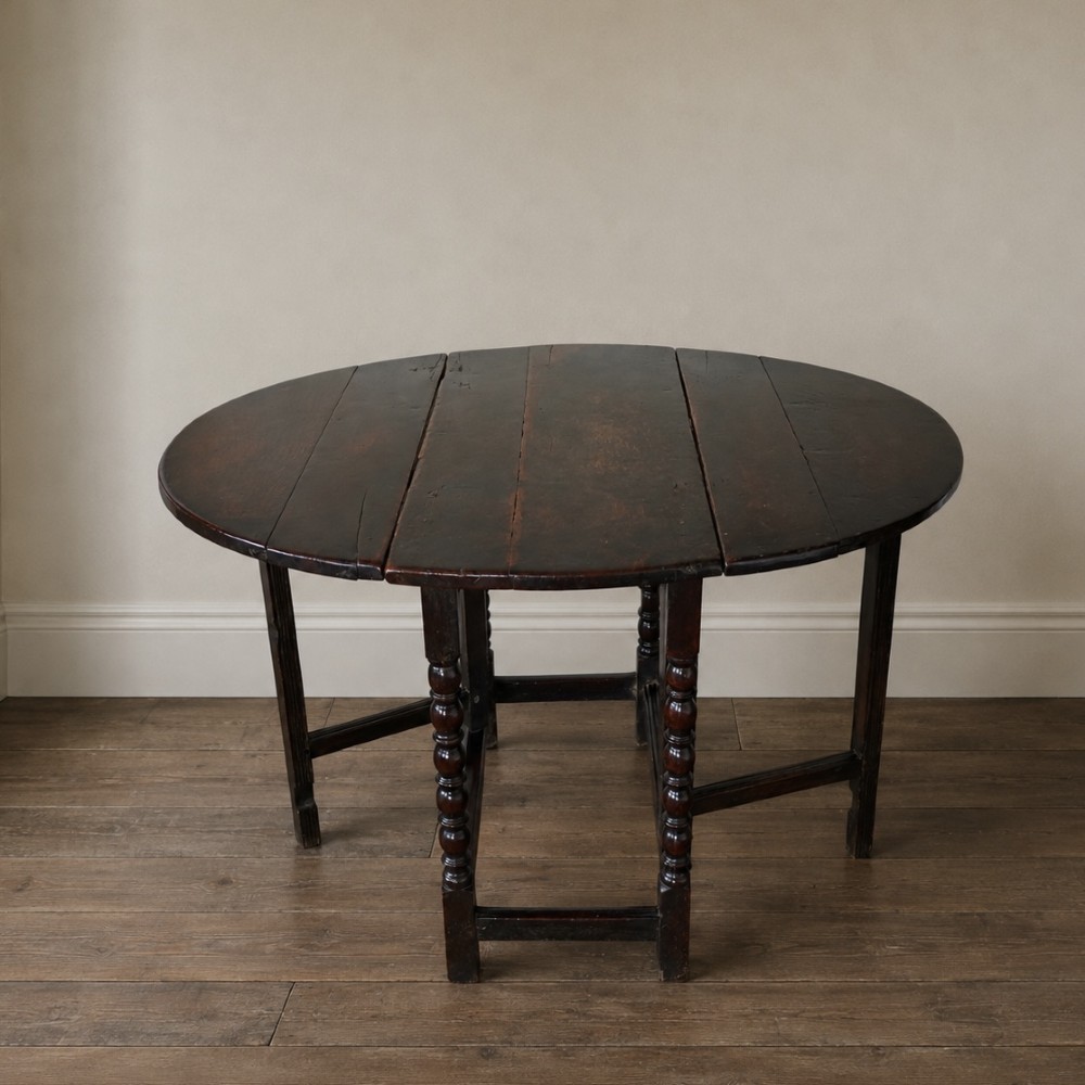 A dark brown antique oak gateleg drop-leaf table with turned legs and an oval top. View XV