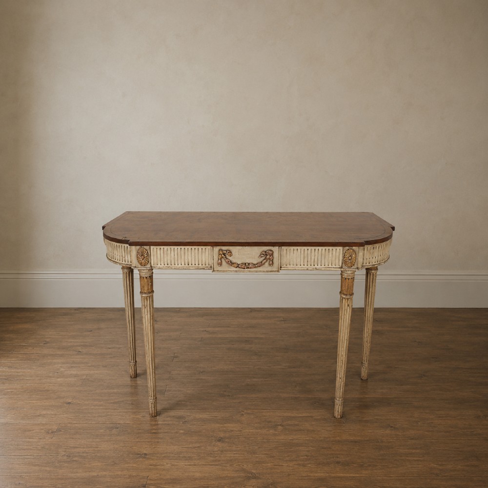 A Georgian style painted cream and gilt console table featuring a dark wood top, fluted legs, and carved swag detailing. View II