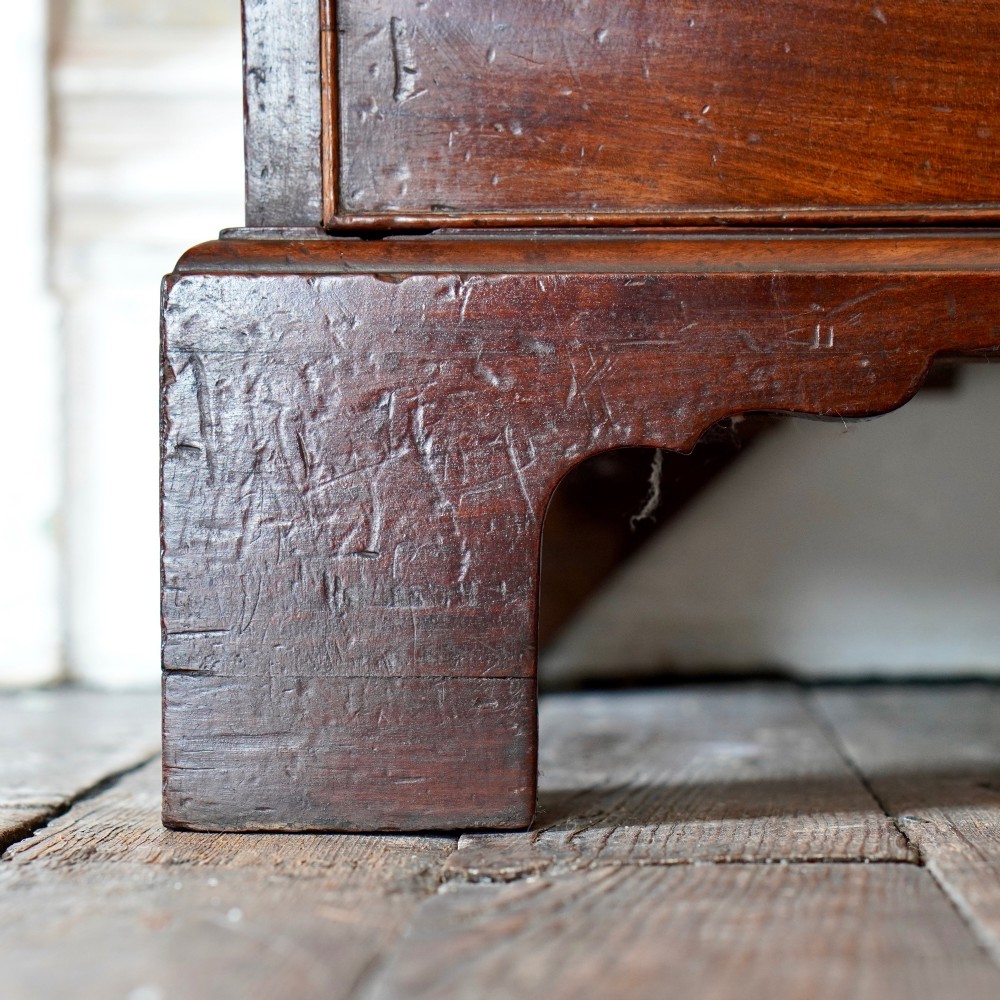 A George II dark mahogany straight-front chest featuring four graduated long drawers with decorative brass swan-neck handles and bracket feet. View X