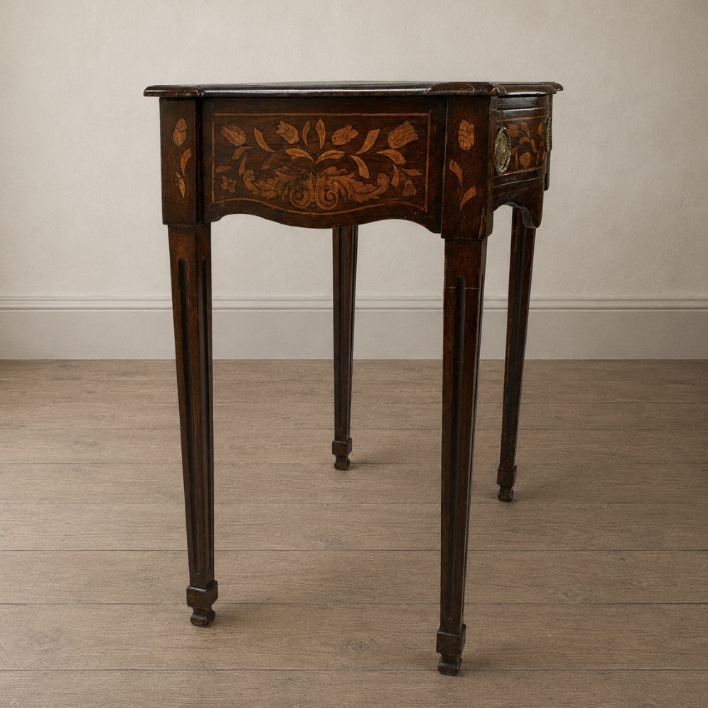 An 18th-century Dutch walnut side table featuring a serpentine front, floral marquetry inlay, a single drawer, and four square tapered legs. View IV