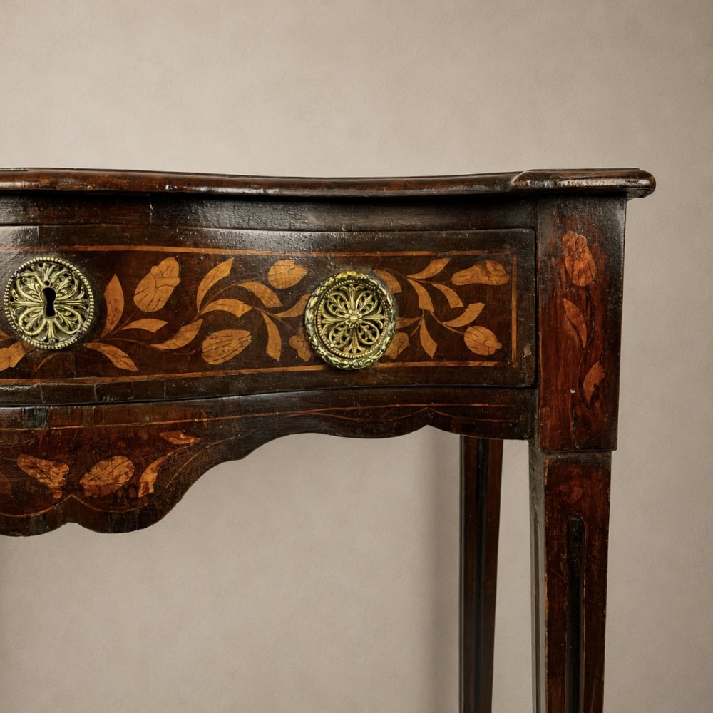An 18th-century Dutch walnut side table featuring a serpentine front, floral marquetry inlay, a single drawer, and four square tapered legs. View VII