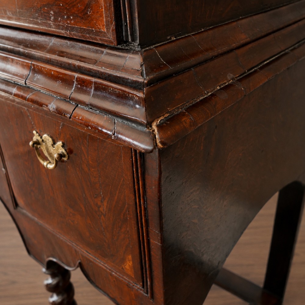 A George I period figured walnut chest on stand featuring engraved brass escutcheons and six barley-twist legs. View XIII