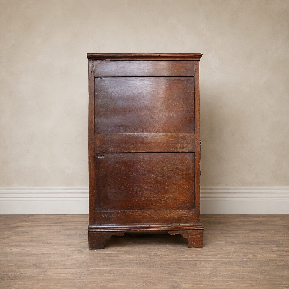 An early eighteenth-century oak chest of drawers featuring four drawers decorated with geometric applied mouldings and brass drop handles. View V