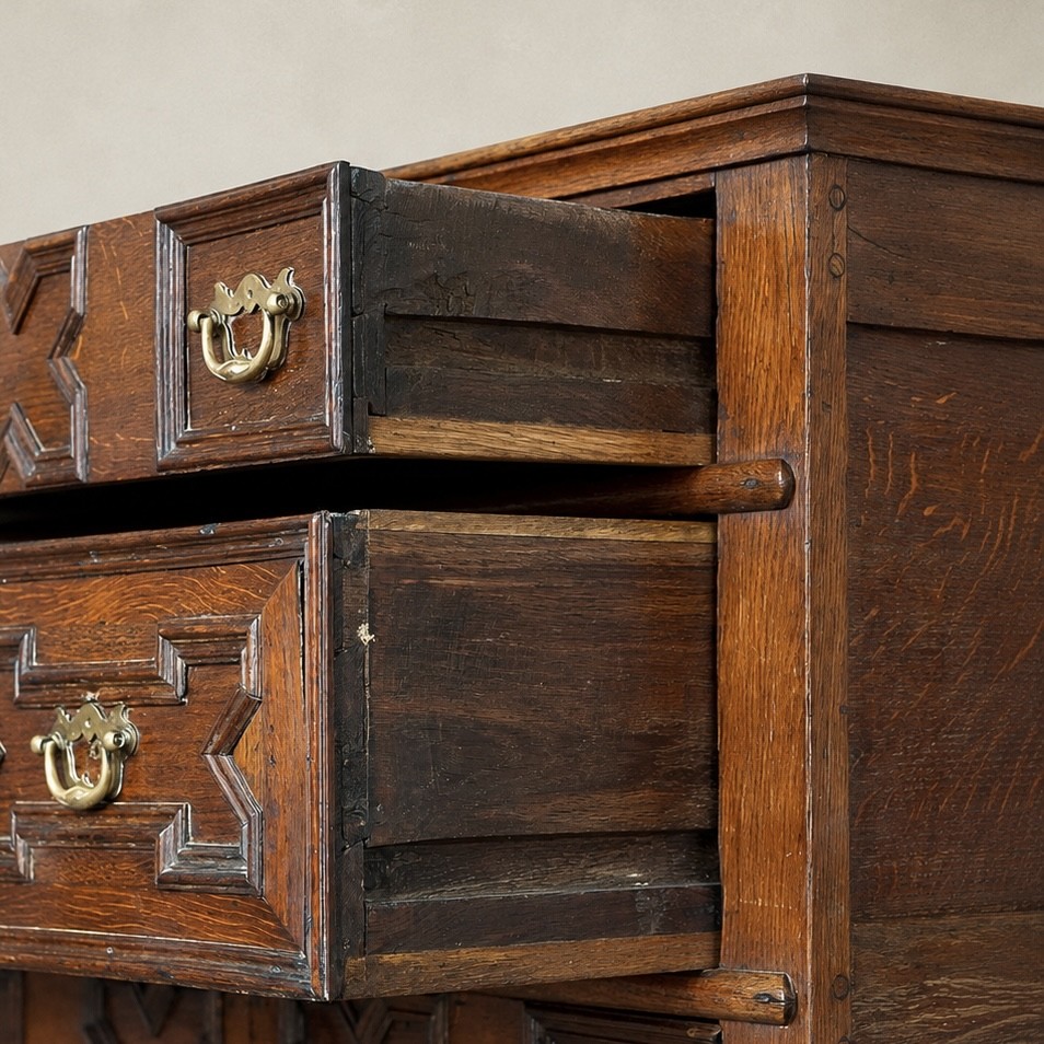 An early eighteenth-century oak chest of drawers featuring four drawers decorated with geometric applied mouldings and brass drop handles. View VIII