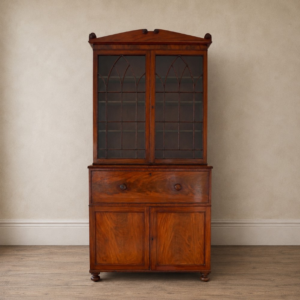 A nineteenth-century George IV mahogany secretaire bookcase with glazed upper doors featuring gothic tracery and a drop-down desk drawer revealing a fitted interior.