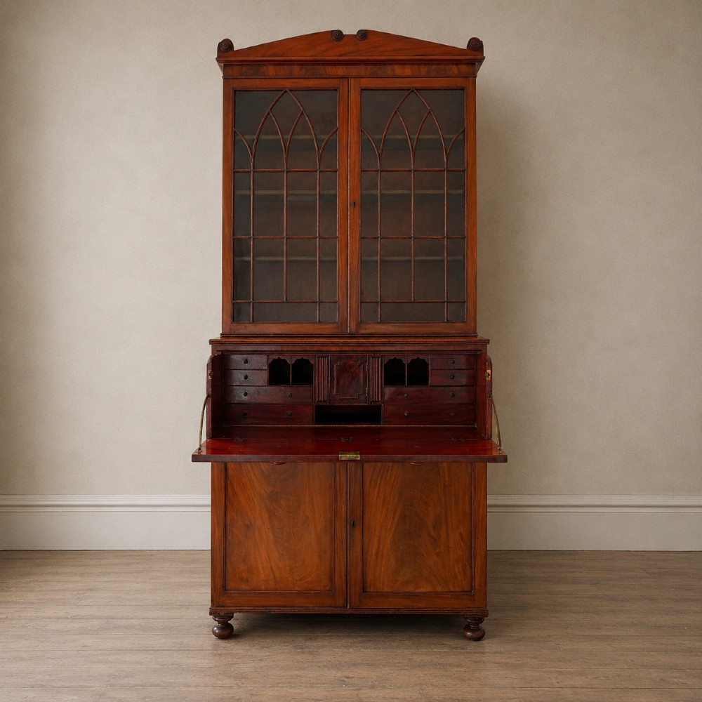 A nineteenth-century George IV mahogany secretaire bookcase with glazed upper doors featuring gothic tracery and a drop-down desk drawer revealing a fitted interior. View IV