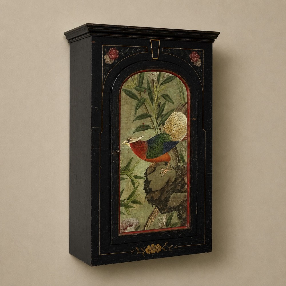 An ebonised black wooden wall cabinet featuring an arched door panel decorated with a hand-painted exotic bird amongst green foliage. View III