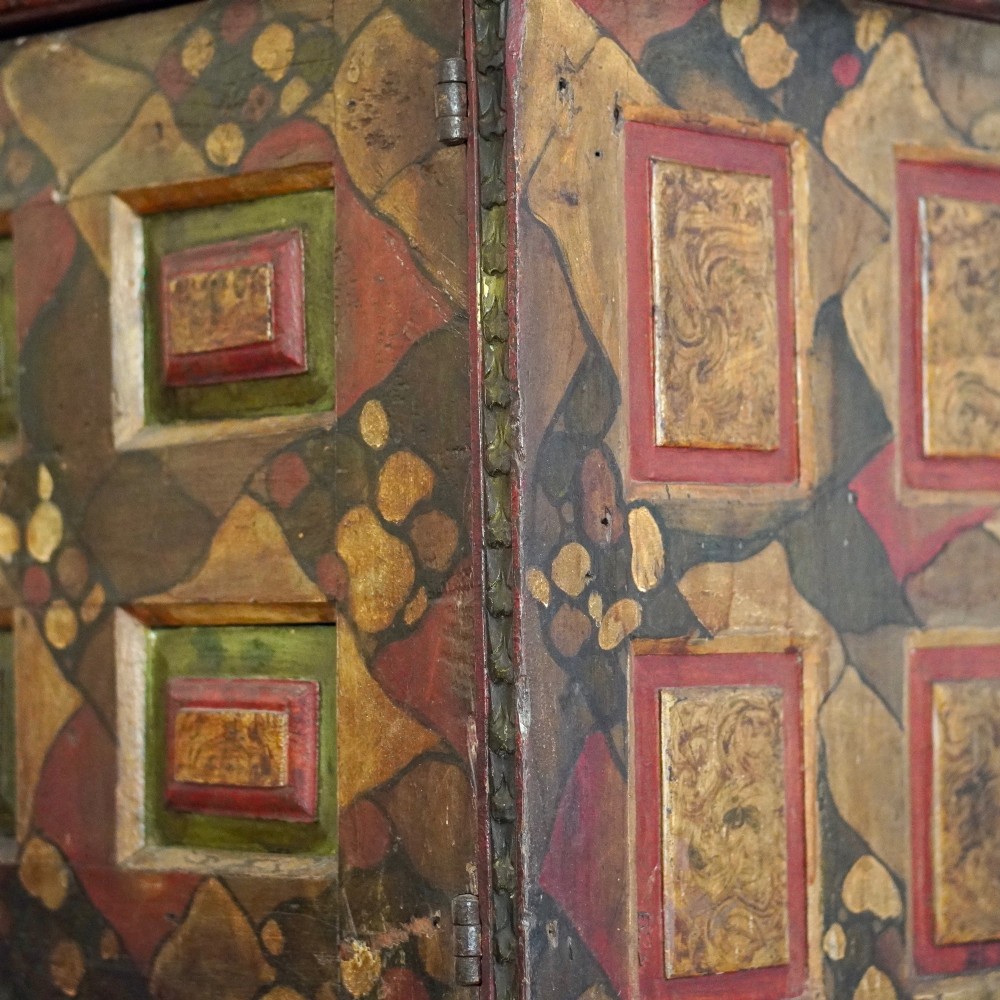 A tall seventeenth-century Spanish oak press cupboard featuring double upper and lower doors decorated with geometric raised panels and painted polychrome geometric patterns. View VI