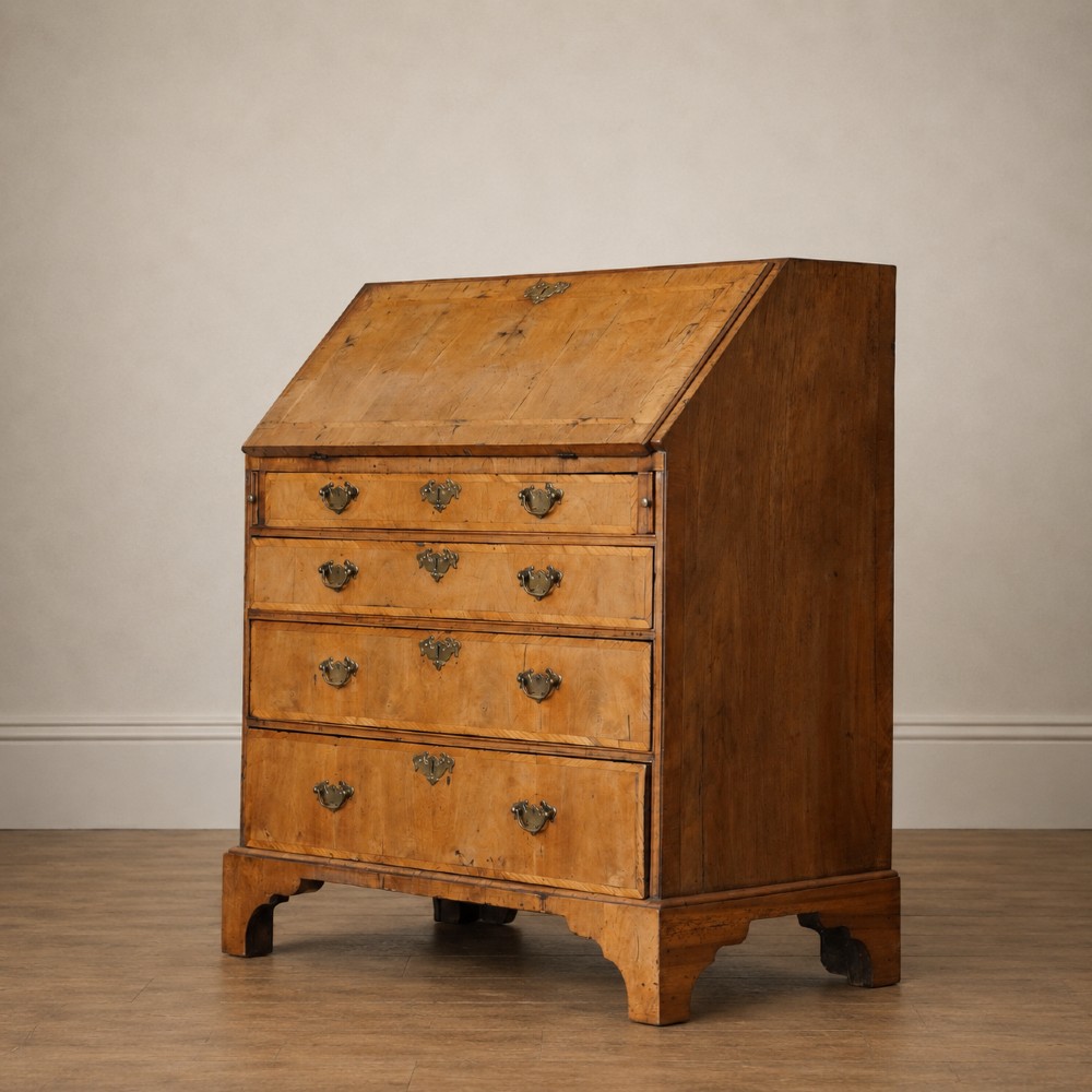 An Early Georgian walnut bureau featuring a sloping drop-front writing lid, four graduated drawers with brass drop handles, and bracket feet. View VII