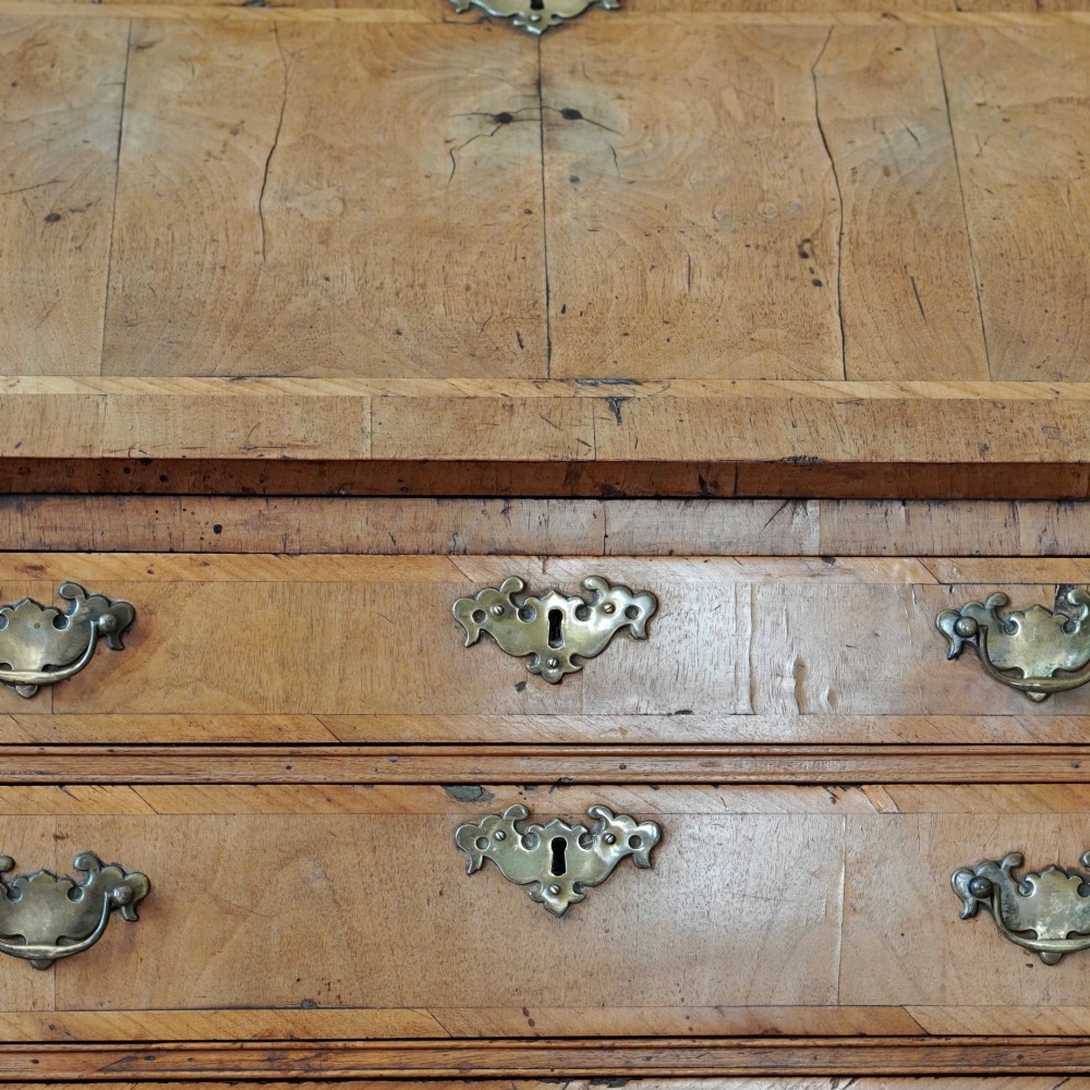 An Early Georgian walnut bureau featuring a sloping drop-front writing lid, four graduated drawers with brass drop handles, and bracket feet. View XII