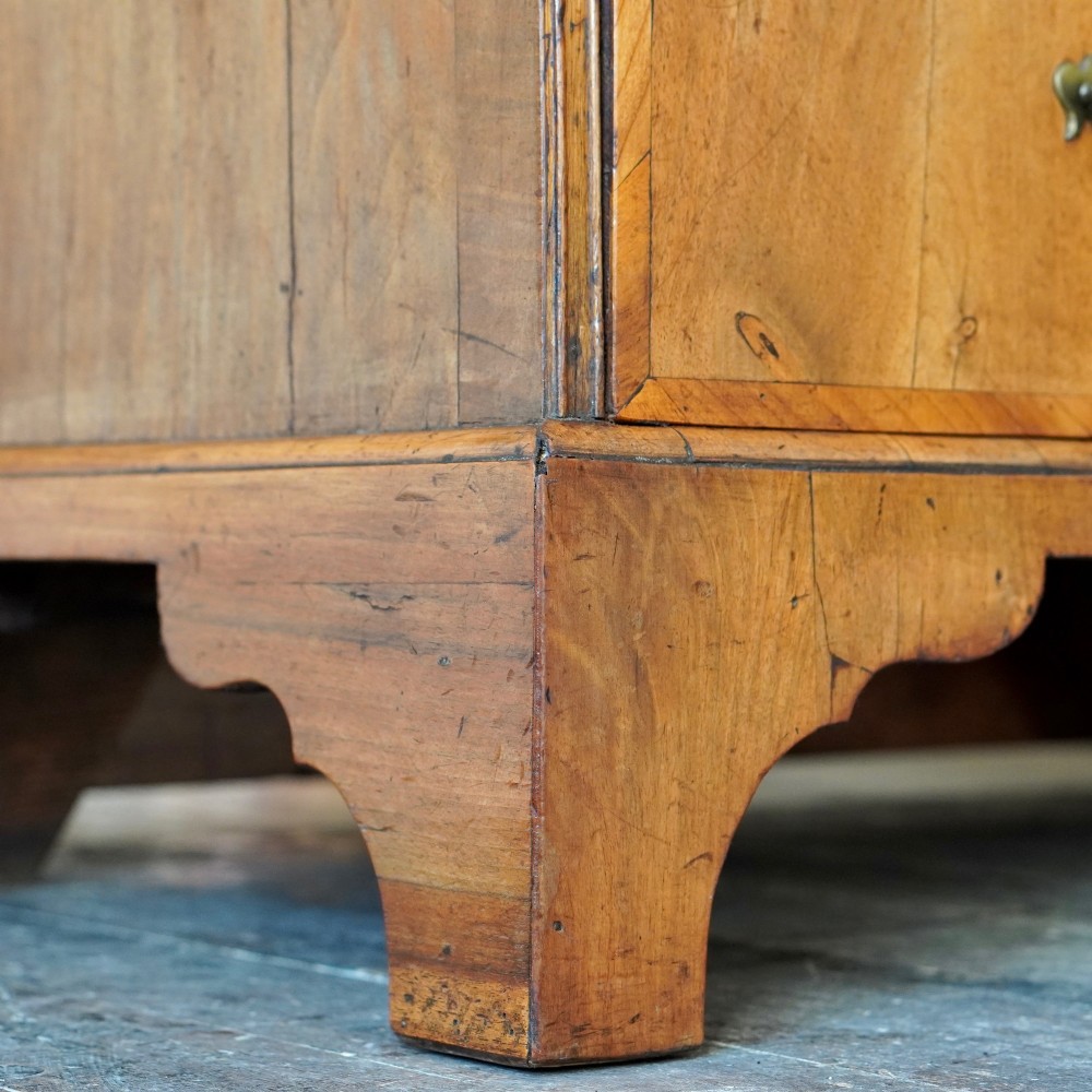 An Early Georgian walnut bureau featuring a sloping drop-front writing lid, four graduated drawers with brass drop handles, and bracket feet. View XIII