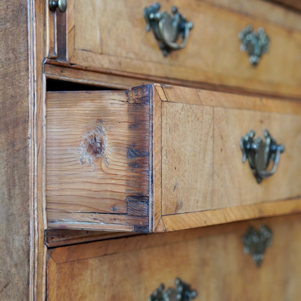 An Early Georgian walnut bureau featuring a sloping drop-front writing lid, four graduated drawers with brass drop handles, and bracket feet. View XIV