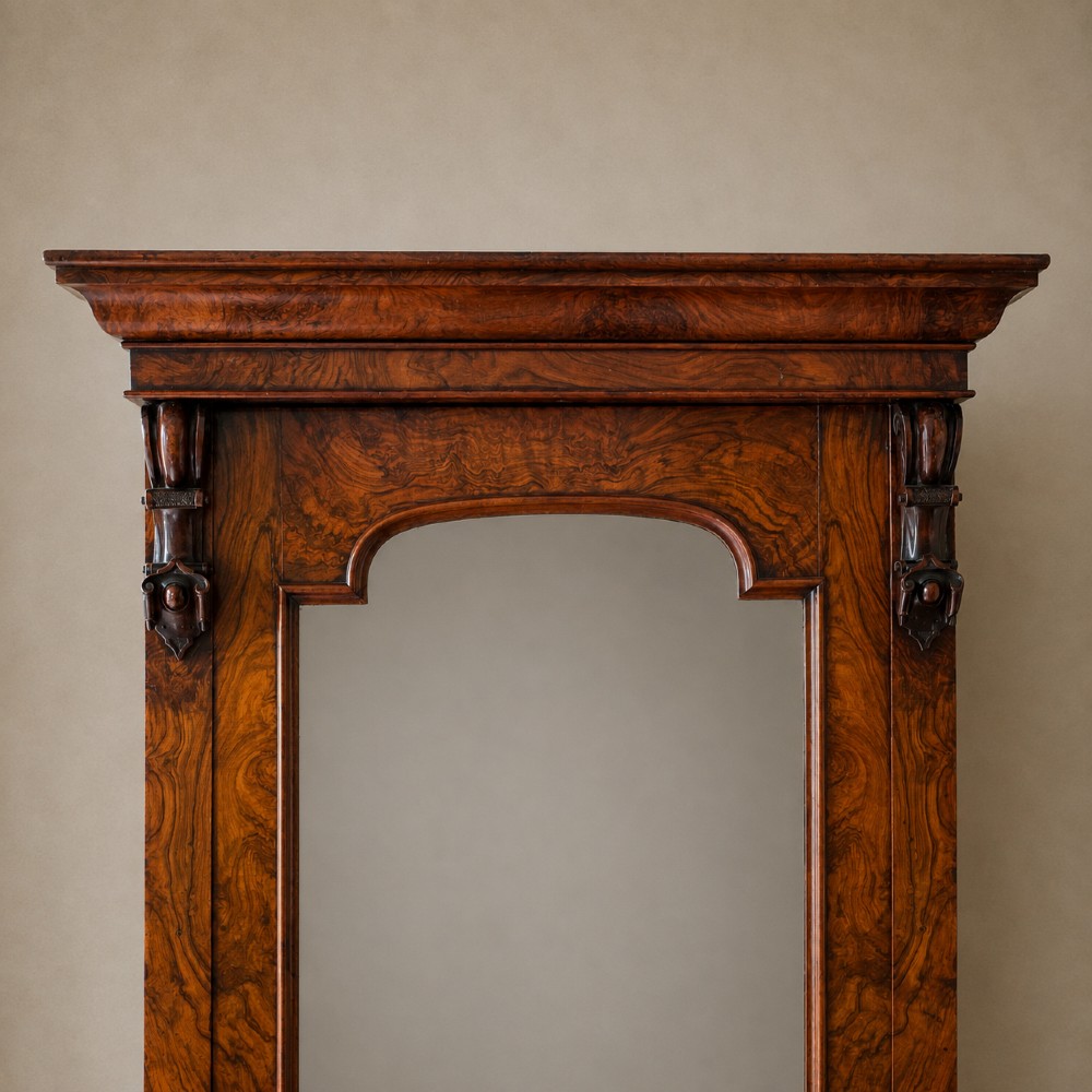 A Victorian single-door wardrobe crafted from figured walnut wood, featuring a central arch-topped mirror panel, carved corbels, and a heavy moulded cornice. View IX