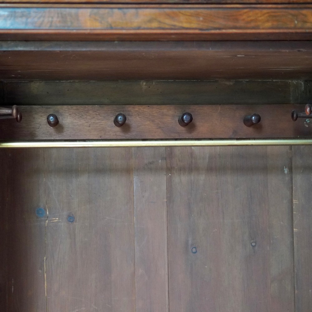 A Victorian single-door wardrobe crafted from figured walnut wood, featuring a central arch-topped mirror panel, carved corbels, and a heavy moulded cornice. View XIII