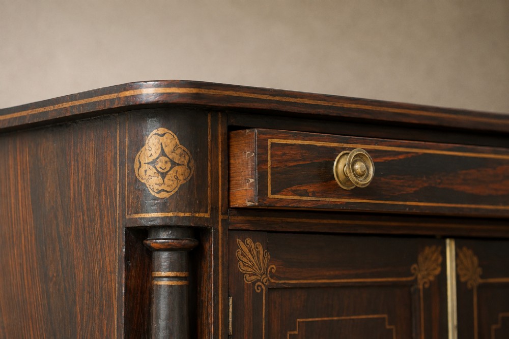 A Regency period side cabinet featuring simulated rosewood graining, gilt corner decorations, turned flanking columns, a top drawer, and two cupboard doors. View VIII