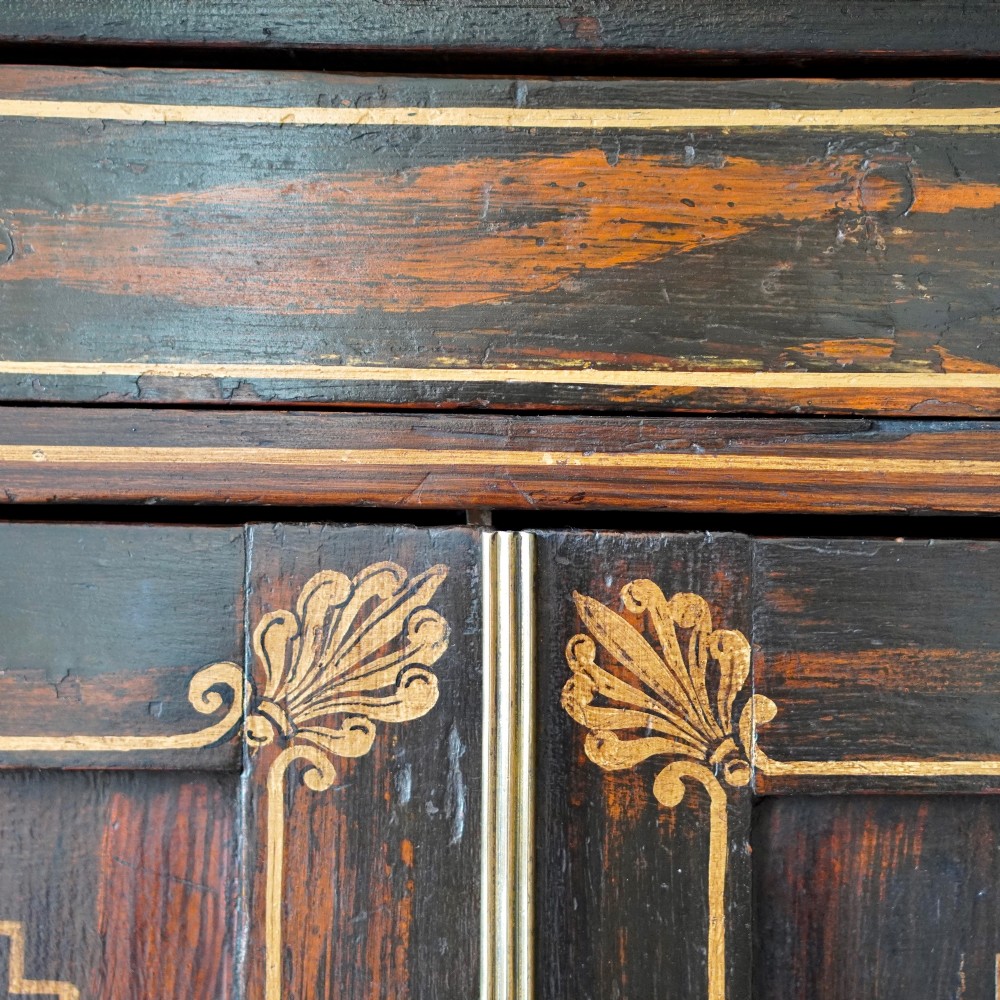 A Regency period side cabinet featuring simulated rosewood graining, gilt corner decorations, turned flanking columns, a top drawer, and two cupboard doors. View XIV