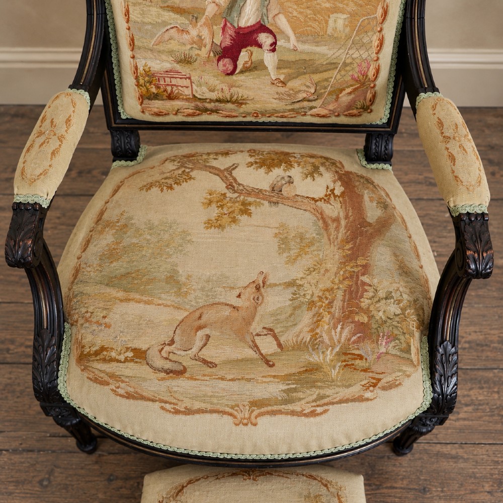 A pair of ebonised beech Louis XVI Revival salon armchairs featuring carved frames, fluted legs, padded armrests, and tapestry upholstery, accompanied by matching footstools. View VIII