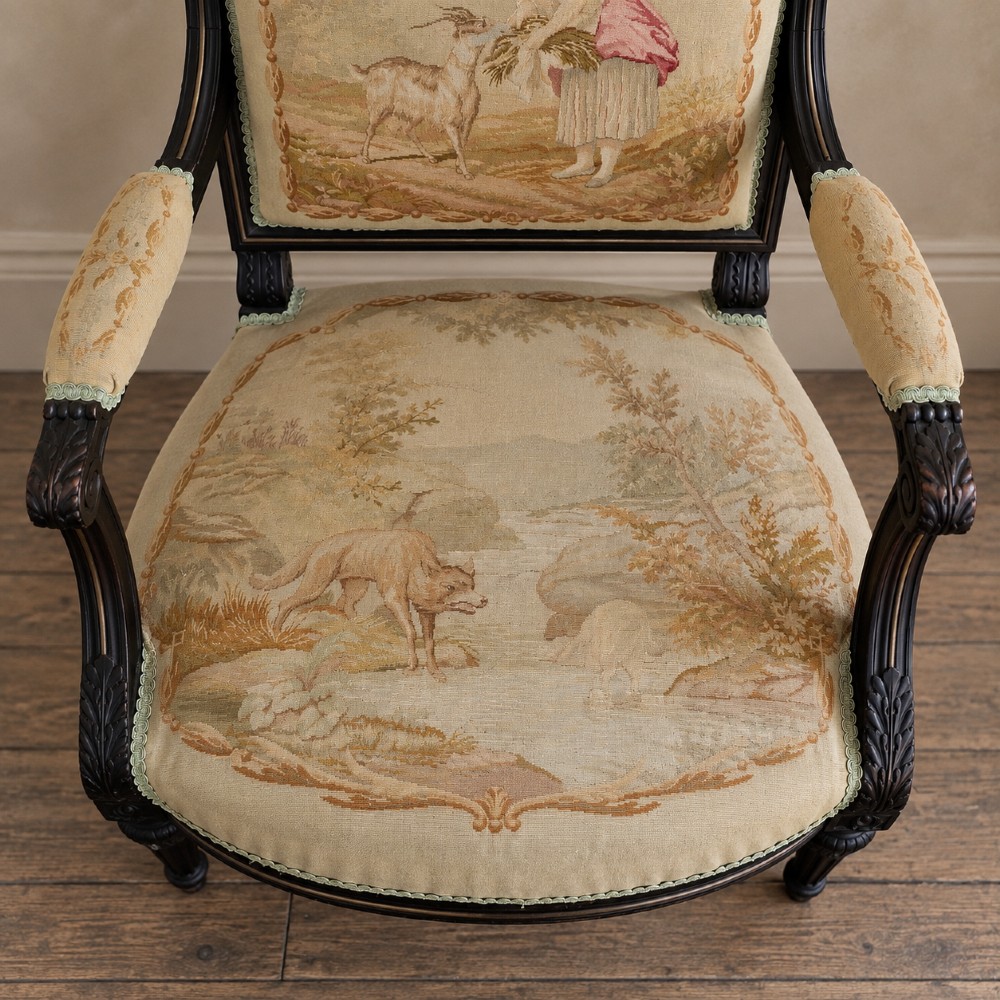 A pair of ebonised beech Louis XVI Revival salon armchairs featuring carved frames, fluted legs, padded armrests, and tapestry upholstery, accompanied by matching footstools. View IX