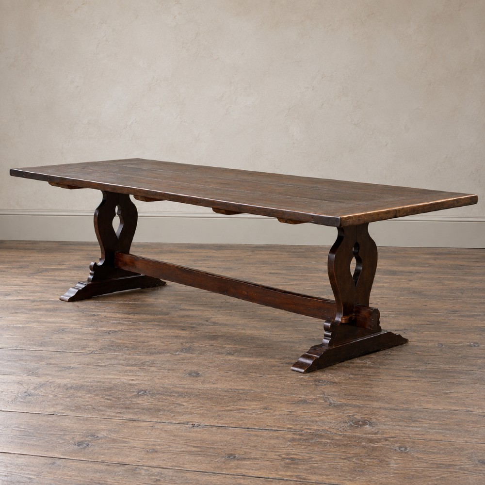 An early twentieth-century dark oak refectory dining table featuring a plank top, pierced trestle end supports, and a central connecting stretcher. View VIII