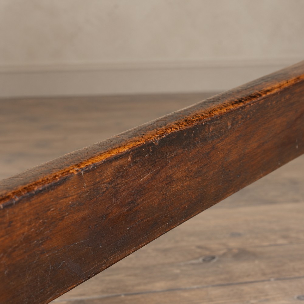 An early twentieth-century dark oak refectory dining table featuring a plank top, pierced trestle end supports, and a central connecting stretcher. View XIV