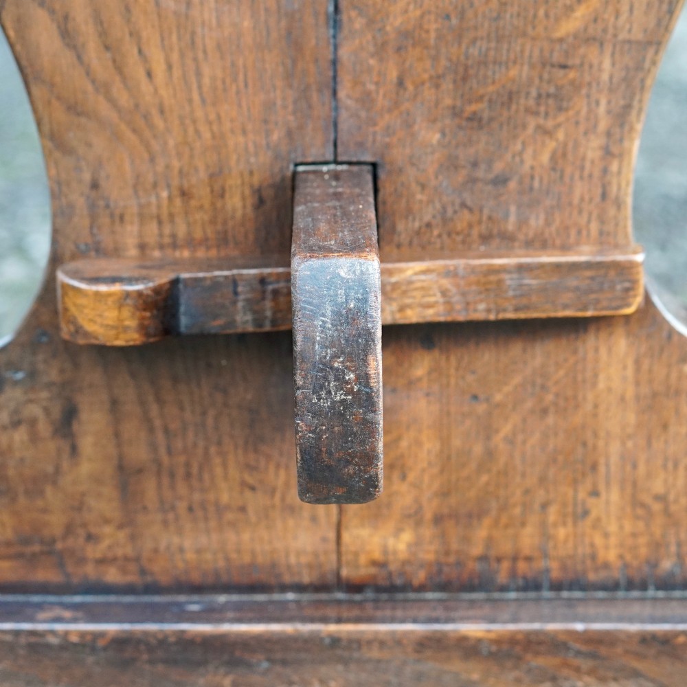 An early twentieth-century dark oak refectory dining table featuring a plank top, pierced trestle end supports, and a central connecting stretcher. View XV