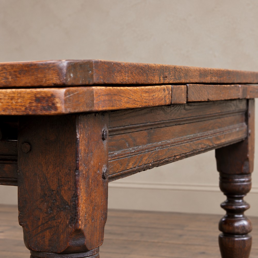 A 17th-century solid oak extending dining table featuring turned legs, lower stretcher rails, and two draw-out end leaves. View III