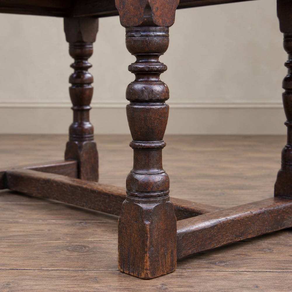 A 17th-century solid oak extending dining table featuring turned legs, lower stretcher rails, and two draw-out end leaves. View V