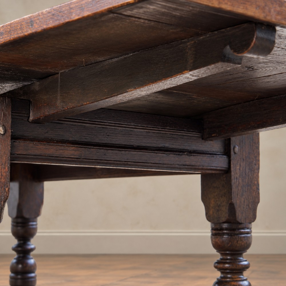 A 17th-century solid oak extending dining table featuring turned legs, lower stretcher rails, and two draw-out end leaves. View X
