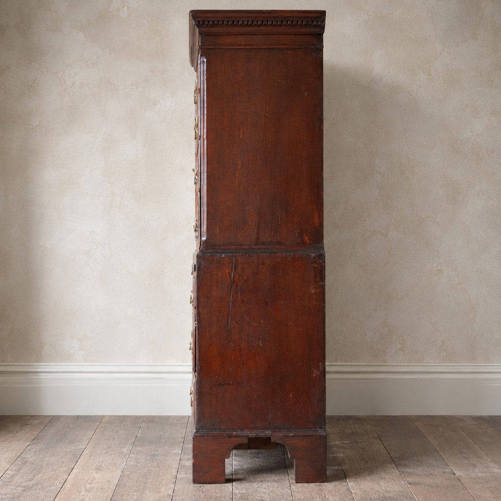 An eighteenth-century Georgian figured mahogany chest on chest featuring a carved dentil cornice, brass swan-neck handles, a pull-out brushing slide, and bracket feet. View III