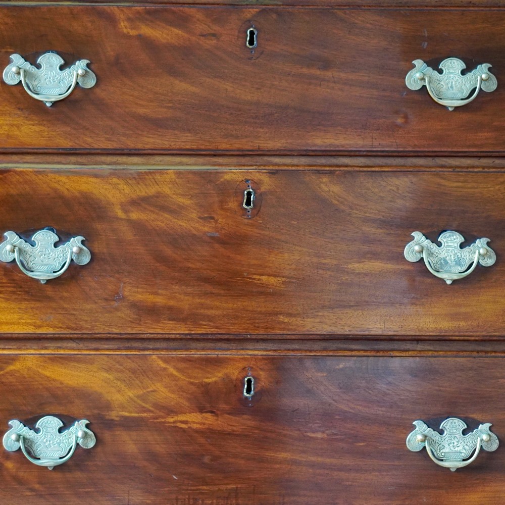 An eighteenth-century Georgian figured mahogany chest on chest featuring a carved dentil cornice, brass swan-neck handles, a pull-out brushing slide, and bracket feet. View IX