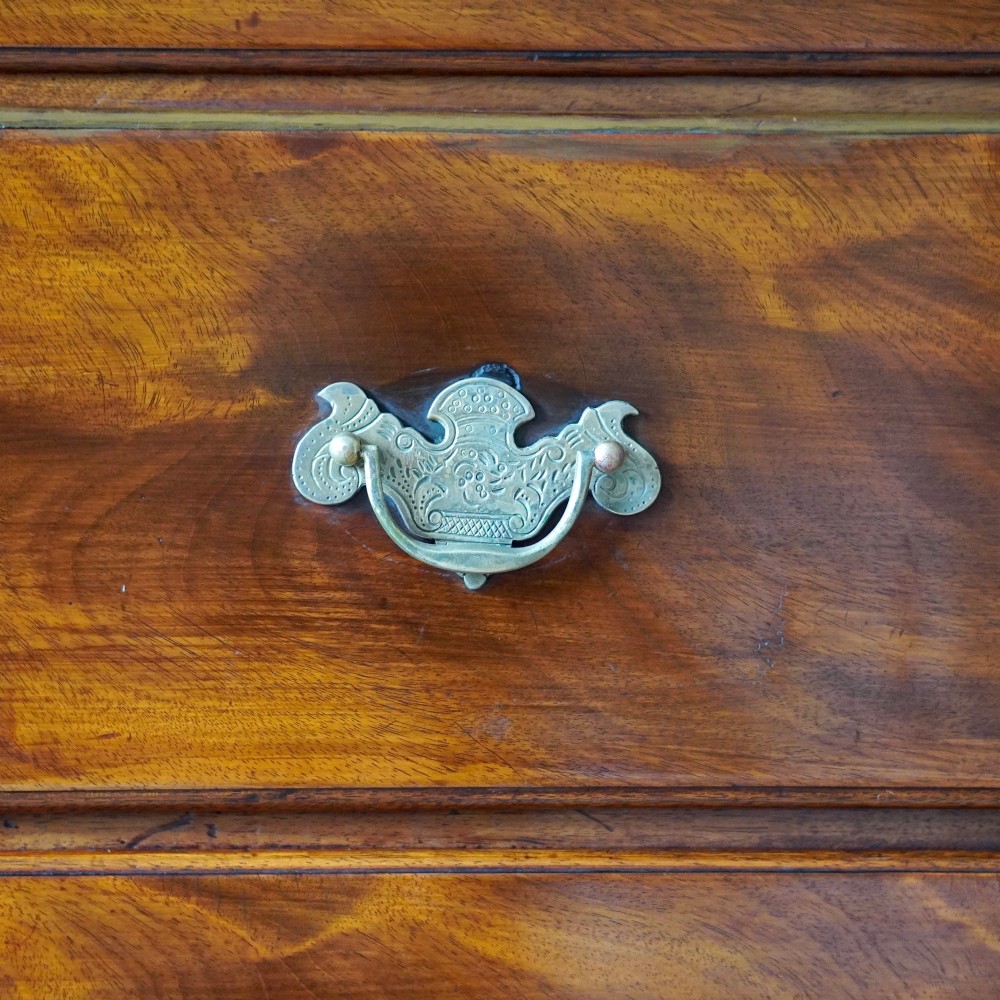 An eighteenth-century Georgian figured mahogany chest on chest featuring a carved dentil cornice, brass swan-neck handles, a pull-out brushing slide, and bracket feet. View X