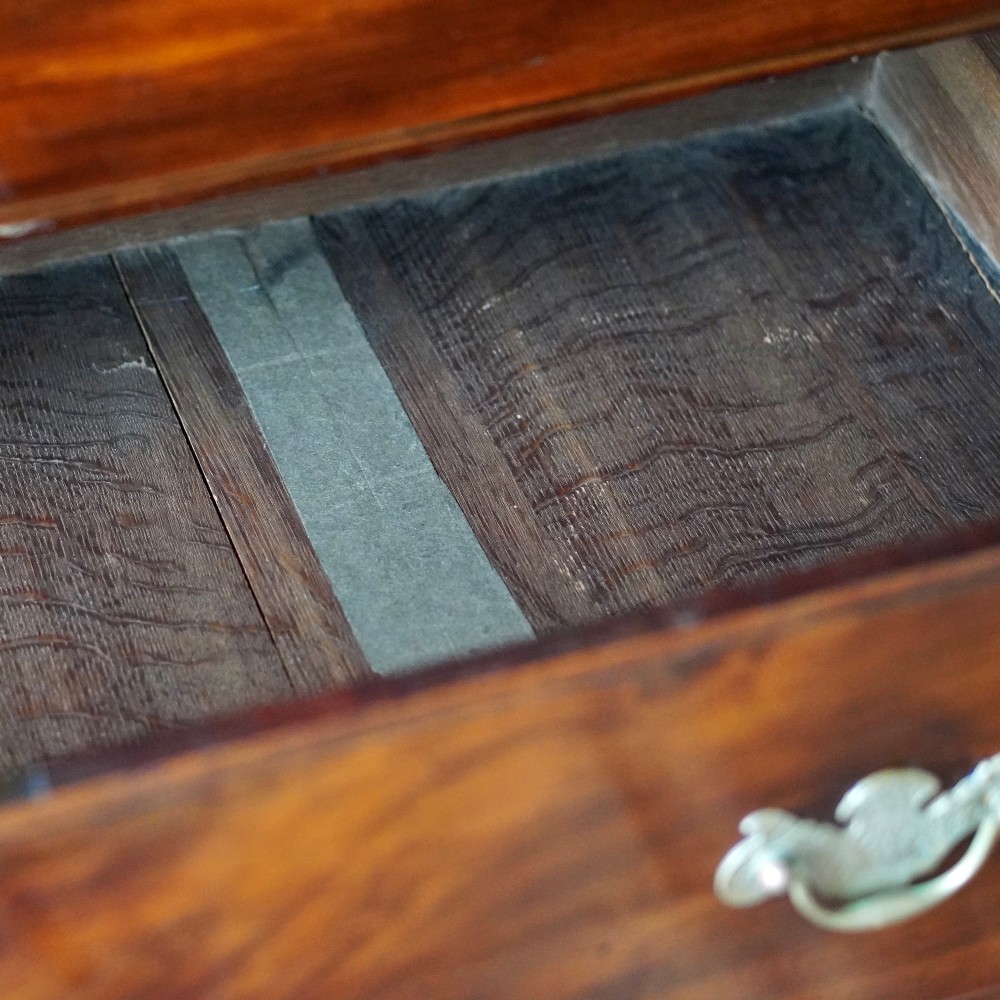 An eighteenth-century Georgian figured mahogany chest on chest featuring a carved dentil cornice, brass swan-neck handles, a pull-out brushing slide, and bracket feet. View XIII