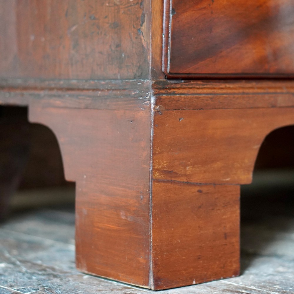 An eighteenth-century Georgian figured mahogany chest on chest featuring a carved dentil cornice, brass swan-neck handles, a pull-out brushing slide, and bracket feet. View XV
