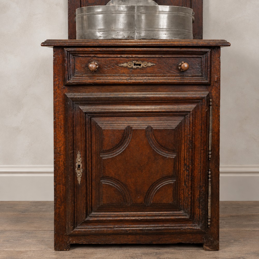 An 18th-century dark chestnut wood lavabo cabinet featuring a carved backboard mounted with a pewter cistern above a matching pewter basin. View VIII