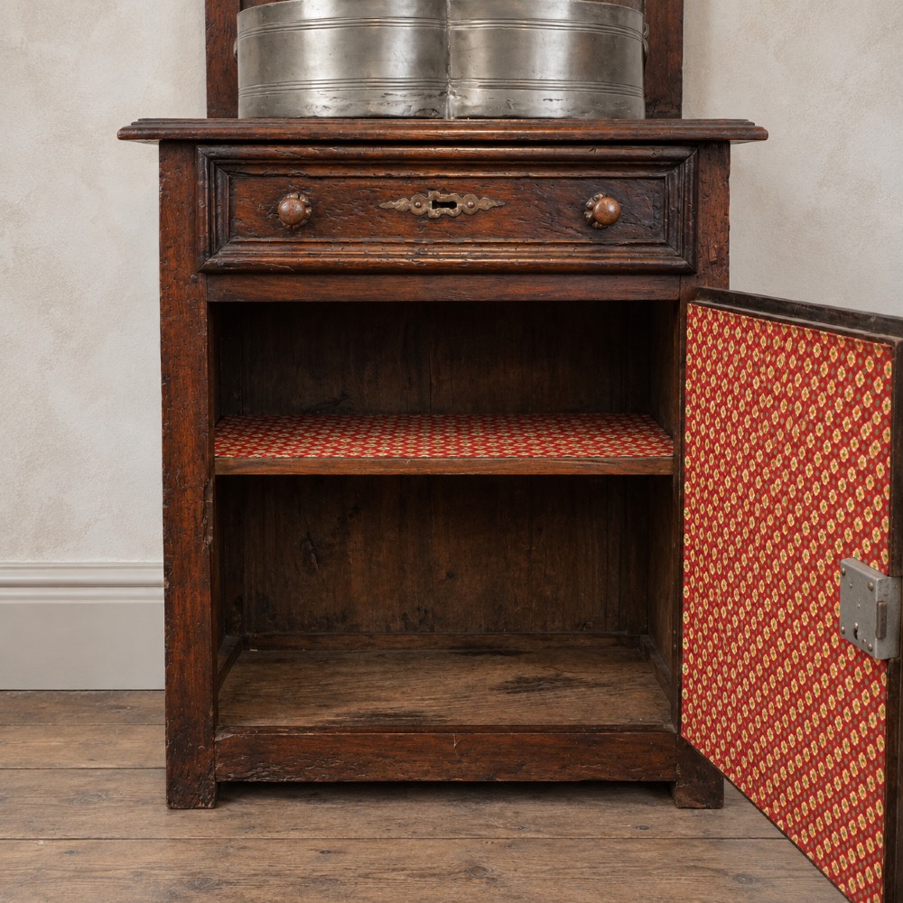 An 18th-century dark chestnut wood lavabo cabinet featuring a carved backboard mounted with a pewter cistern above a matching pewter basin. View X