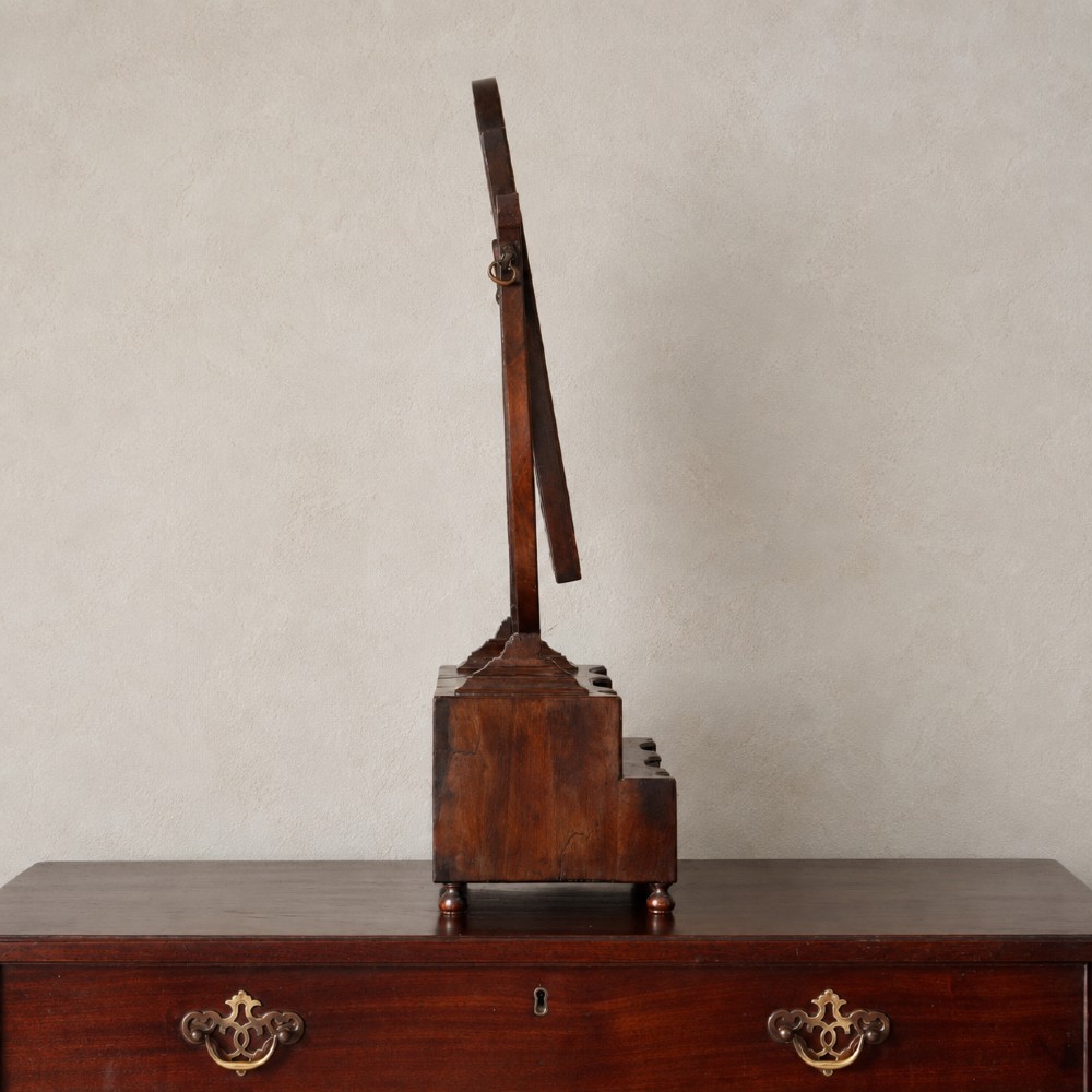 An antique Queen Anne walnut and laburnum toilet mirror featuring an arched cross-banded frame above a serpentine base with miniature drawers. View III