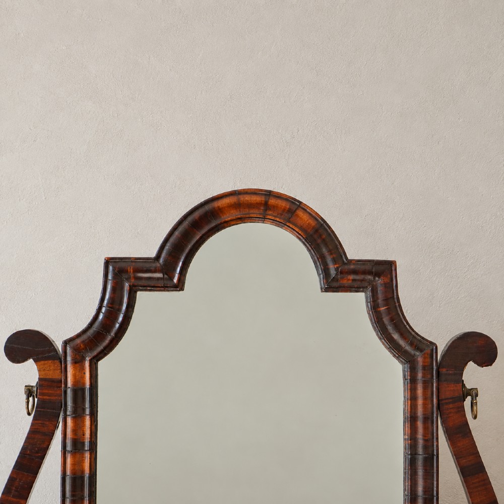 An antique Queen Anne walnut and laburnum toilet mirror featuring an arched cross-banded frame above a serpentine base with miniature drawers. View V