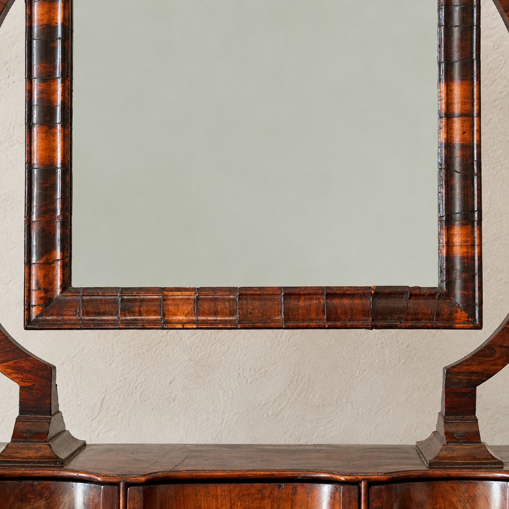 An antique Queen Anne walnut and laburnum toilet mirror featuring an arched cross-banded frame above a serpentine base with miniature drawers. View VIII