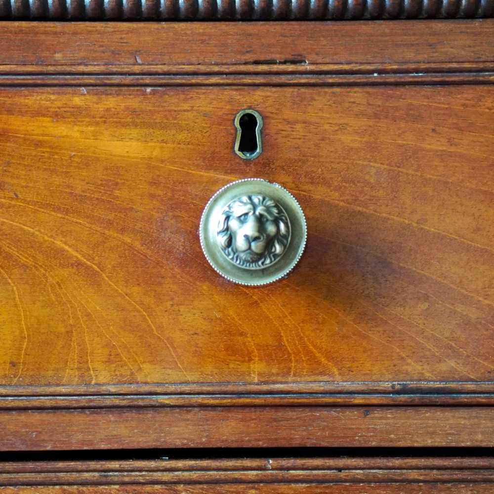 A Regency period flame mahogany linen press featuring a two-door upper cupboard above four drawers resting on turned legs. View X