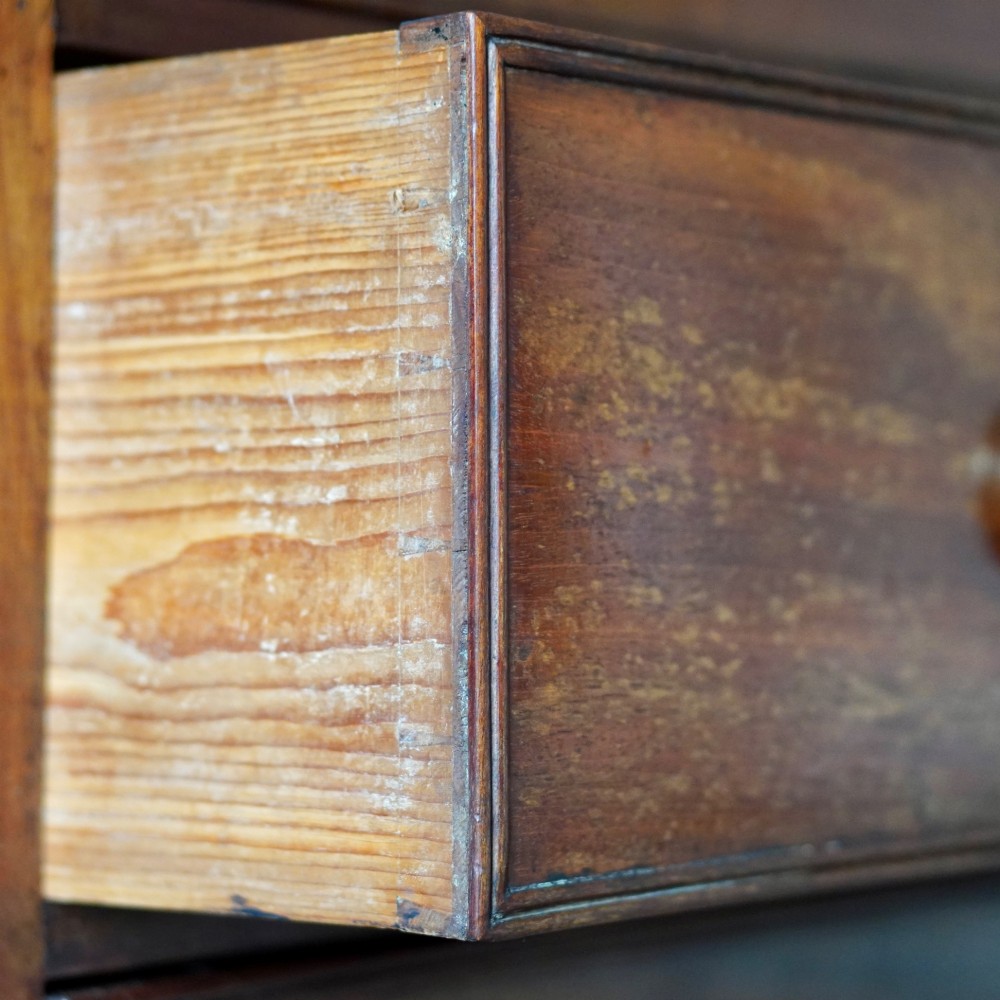 A Regency period flame mahogany linen press featuring a two-door upper cupboard above four drawers resting on turned legs. View XIII
