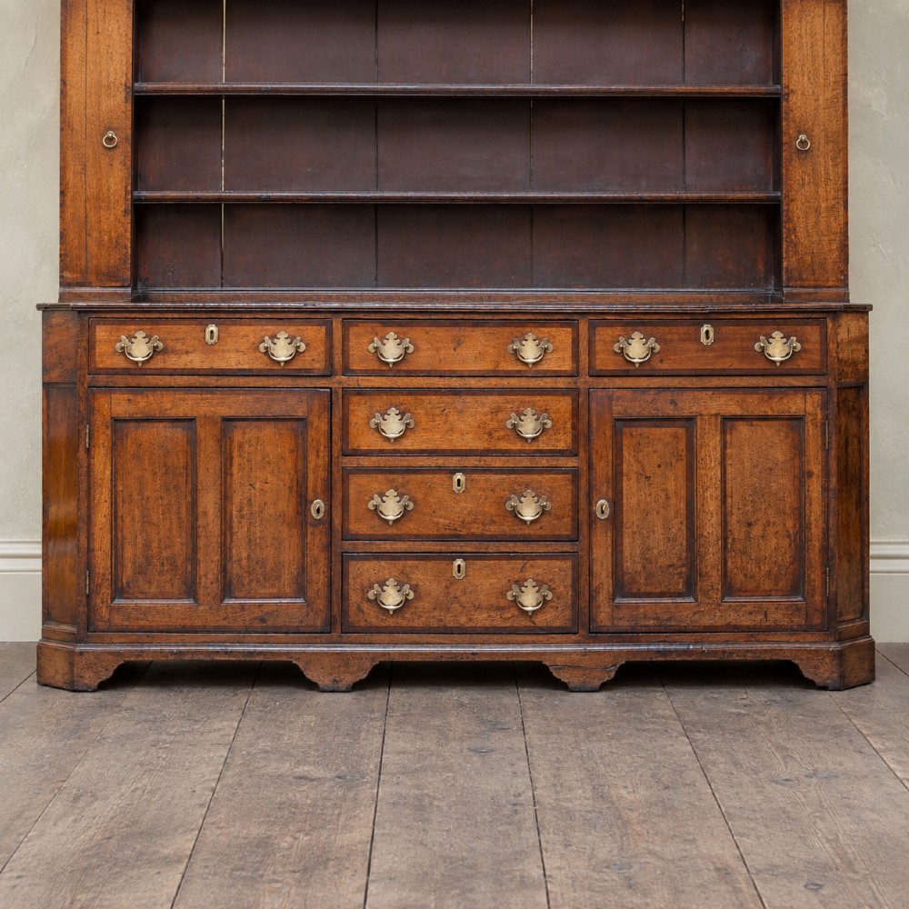 A George II dark oak dresser with a tall open plate rack above a sideboard featuring multiple drawers and twin cupboard doors. View II