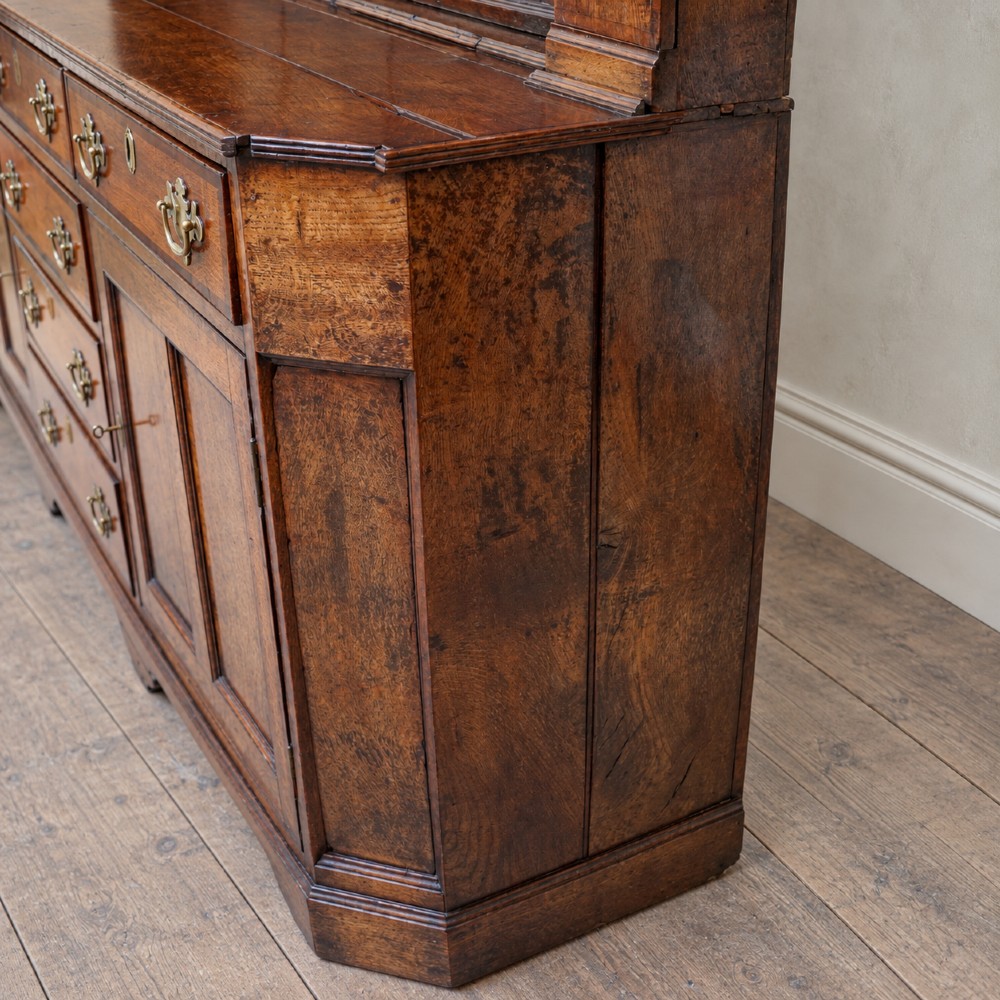 A George II dark oak dresser with a tall open plate rack above a sideboard featuring multiple drawers and twin cupboard doors. View IV