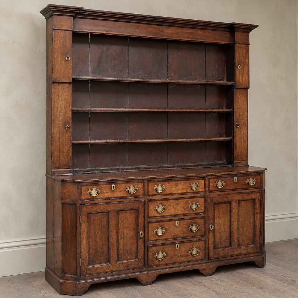 A George II dark oak dresser with a tall open plate rack above a sideboard featuring multiple drawers and twin cupboard doors. View V
