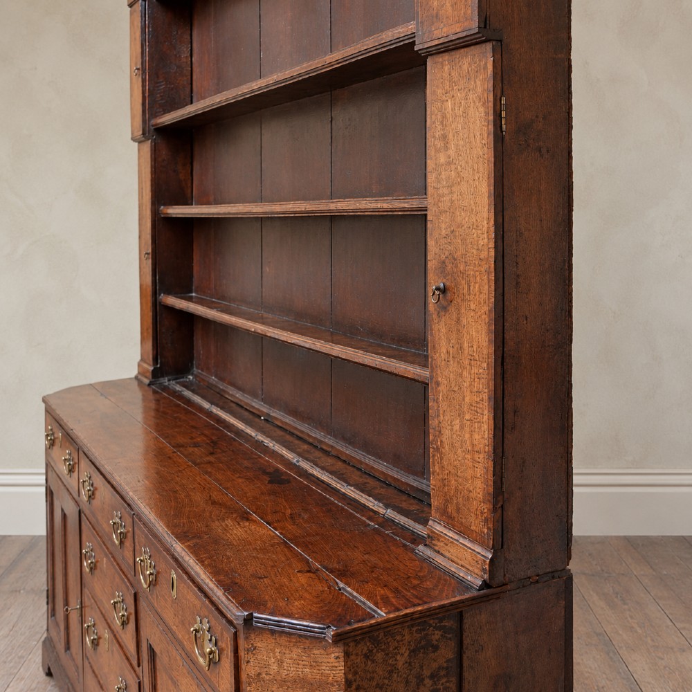 A George II dark oak dresser with a tall open plate rack above a sideboard featuring multiple drawers and twin cupboard doors. View VI